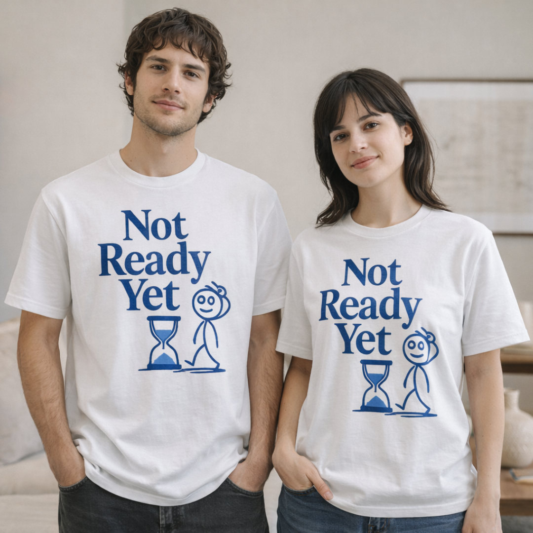 Männliches und weibliches Model tragen weißes „Not Ready Yet“ Organic T-Shirt mit blauem Print, locker geschnitten, aufgenommen in hellem Innenraum