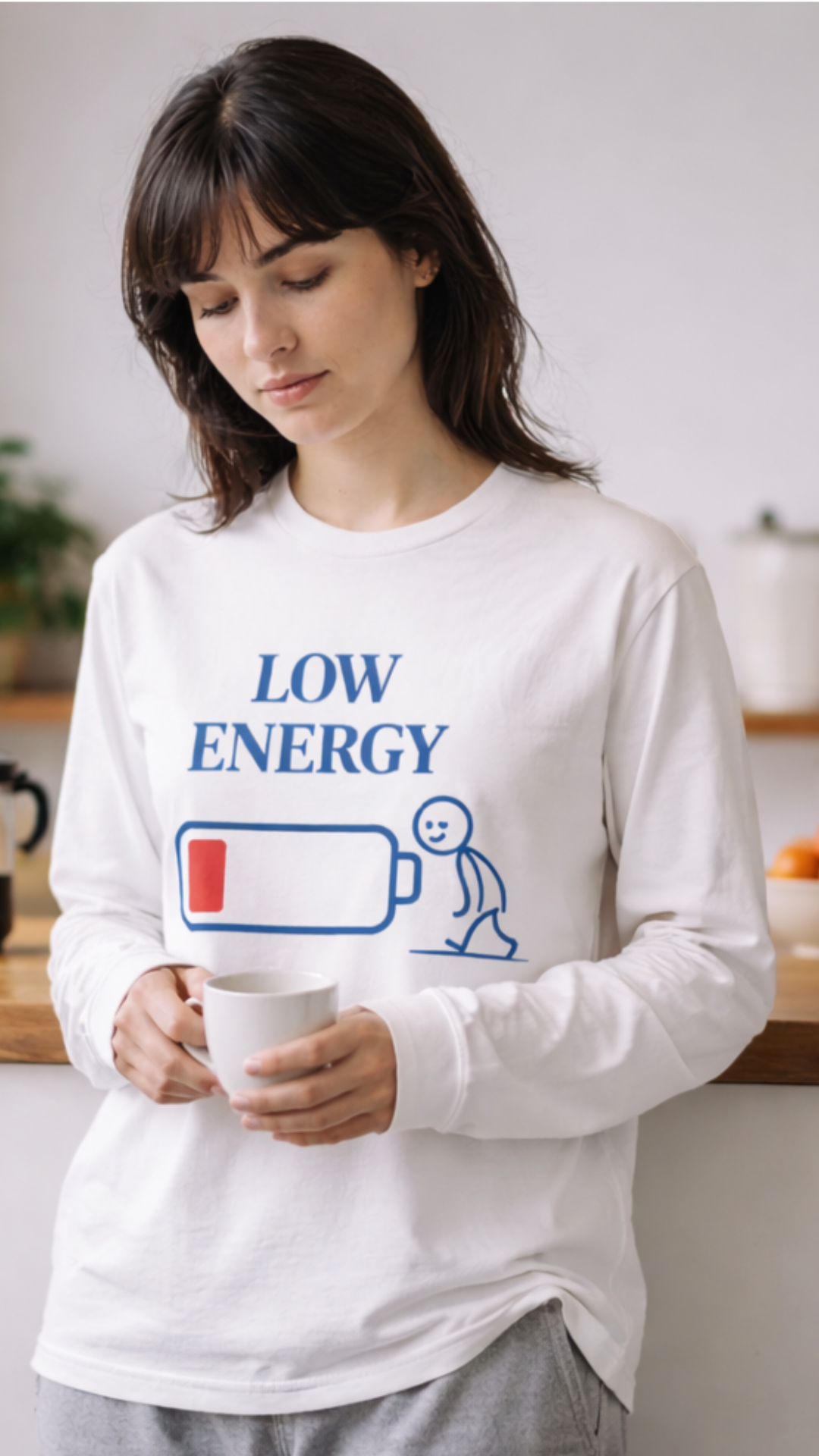 Frau trägt weißes LOW ENERGY Organic Longsleeve T-Shirt mit blauem Print und Batteriemotiv, locker geschnitten, minimalistisches Alltags-Outfit